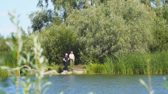 Fisherman on the Shore of a Lake or River with a Fishing Rod Catches Fish alt