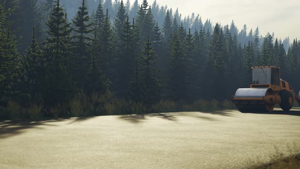 Four yellow road rollers paving the asphalt road in the coniferous forest. alt