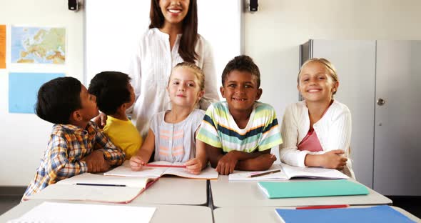 Portrait of teacher and school kids in classroom alt