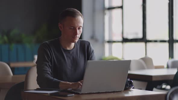 A Serious Man is a Business Student Working Studying Sitting at a Table and Typing a Message on a alt