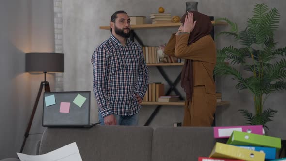 Wide Shot of Angry Irritated Middle Eastern Husband and Wife Arguing in Home Office Indoors alt