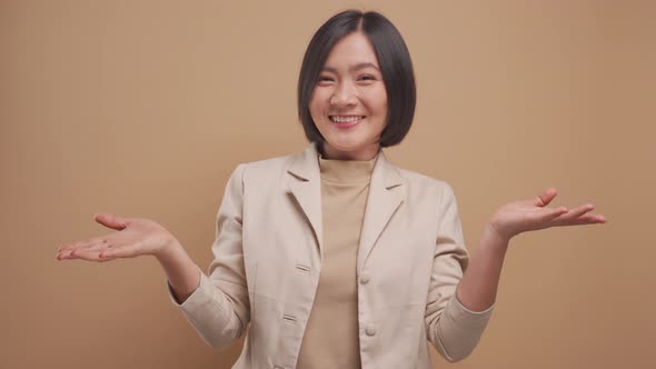 Asian business woman shrugs her arms and makes gesturing of she don't know standing isolated