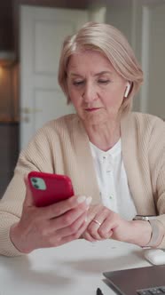An Elderly Woman Sits Near a Laptop alt