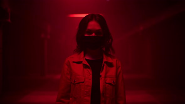 Woman Standing Wearing Protective Face Mask in a Red Light of Dark Underground Tunnel and Looking at alt