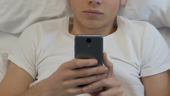 Teenage Boy Playing  Smartphone Games at Night, Downloading Applications alt