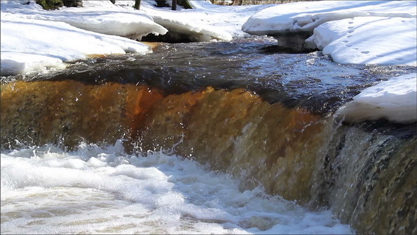 A Clear Water Flowing Between the Snow-Covered  