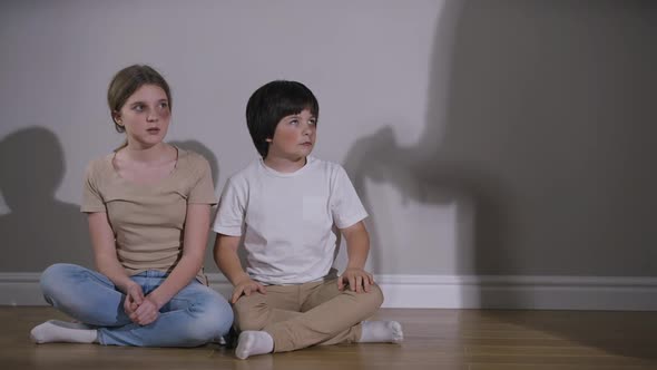 Caucasian Brother Hugging Sister As Shadow of Violent Aggressive Parent Threatening with Belt alt