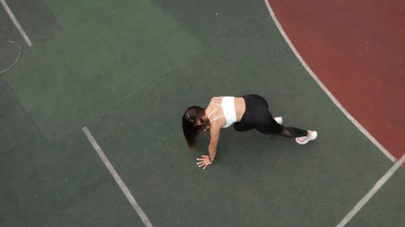 Young Woman Is Doing Plank Exersice Flexing Legs in Dynamic on Sport Ground
