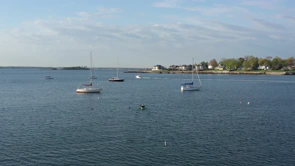 A low altitude drone shot over calm with a few sailboats in the water. The camera dolly in behind a alt