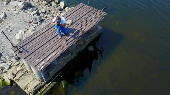 Man Taking Photos Near Pond. Photographer photographing landscape near river alt
