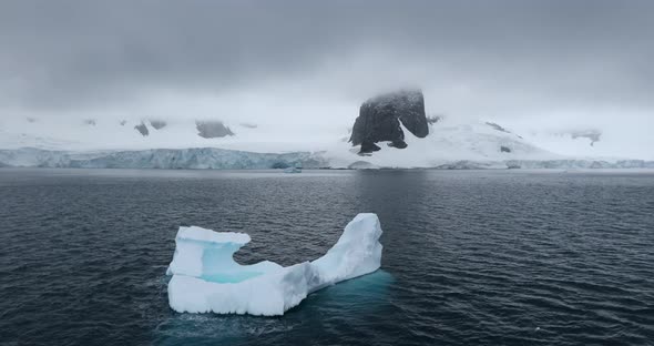 WS Iceberg and snow covered coast of Cuverville Island on cloudy day / Antarctica