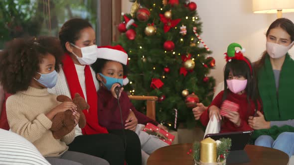 Group of mothers and kids wearing masks celebrating Christmas in the time of pandemic