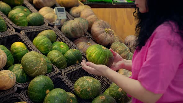 Young Woman Buys Groceries Chooses a Pumpkin in the Supermarket for a Hollowin Holiday alt