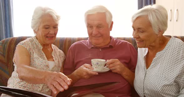 Happy senior friends looking at a photo album alt