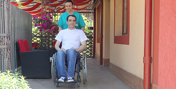 Nurse Walking with Male Patient in a Wheelchair alt