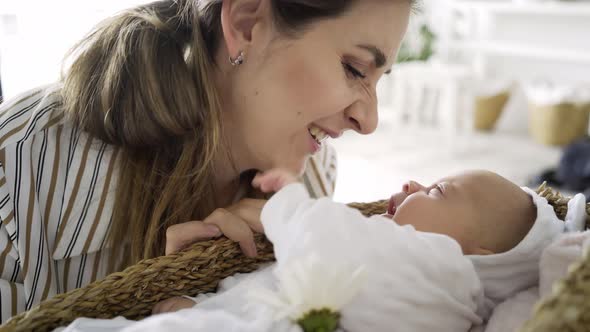 Brunette in Striped Dress Lulls Funny Little Baby in Basket