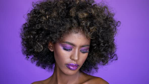 Portrait of Beautiful African American Female Model with Afro Hair and Glowing Purple Makeup