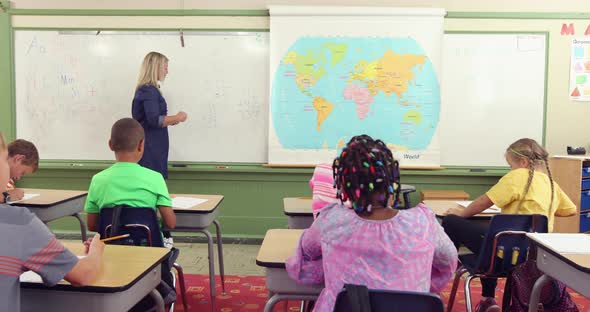 Teacher in front of class asking math questions alt