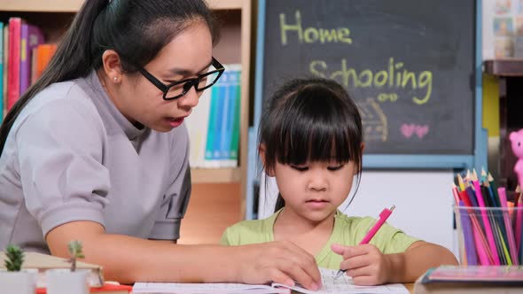 Asian little girl studies at home during quarantine with her mother.