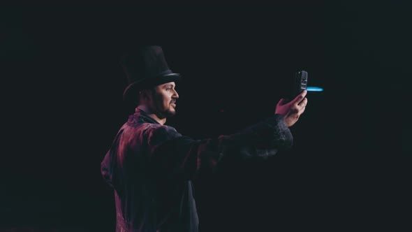 a man in a suit takes a selfie on his phone. theatre actor