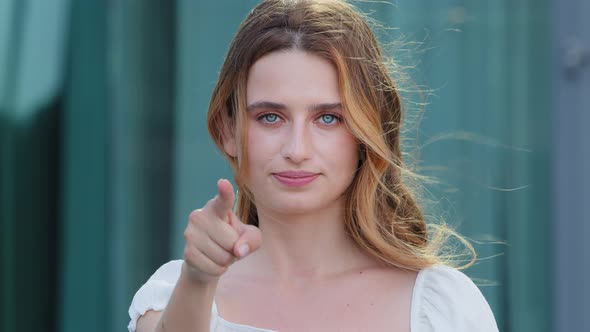 Young Blonde Girl with Blond Hair in Summer Clothes Looking at Camera Pointing Index Finger at alt