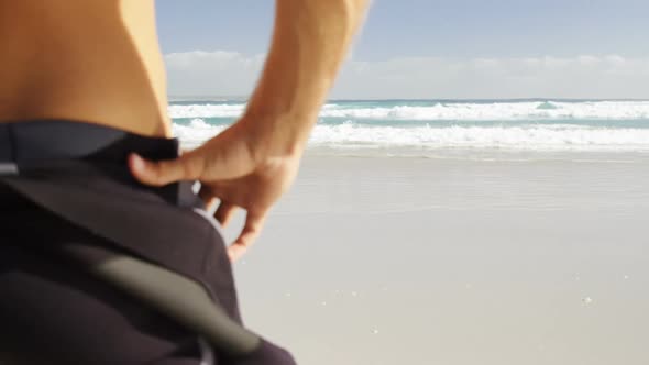 Rear view of male surfer standing in the beach alt