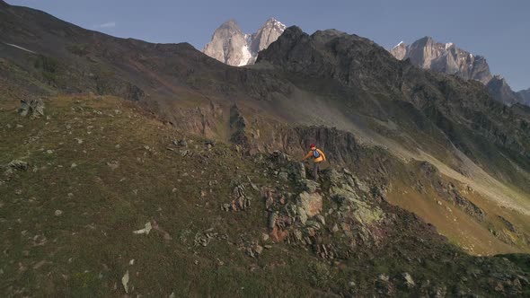 Aerial Slow-motion Shot of a Man Climbing Mountains on a Sunny Day in Autumn.