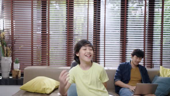 Happy asian family seeing son dancing in the living room at home