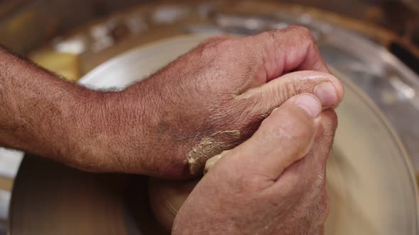 Artisan Holds Wet Piece of Clay on Pottery Wheel with Both Hands and Gives It Round Shape Closeup alt