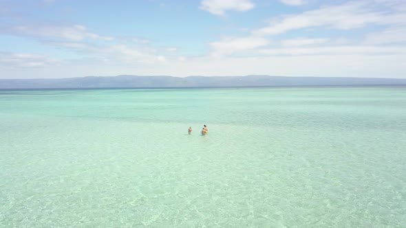Aerial Cinematic Group of Tourists Standing and Swimming in the Beach Resort alt