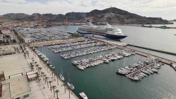 Orbiting over sailboats on Cartagena recreational harbor, Cruise ship ready to departure. Spain