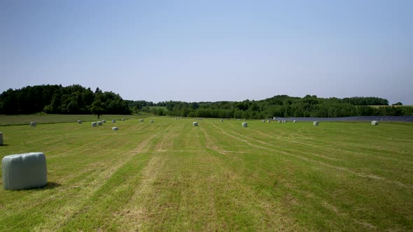 Agricultural field after harvesting crops with hay bales wrapped in white plastic bags -aerial alt