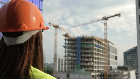 Female Builder at a Construction Site Oversees the Progress of Construction Work