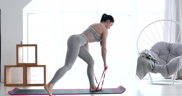 Woman doing exercises with resistance bands at home. alt