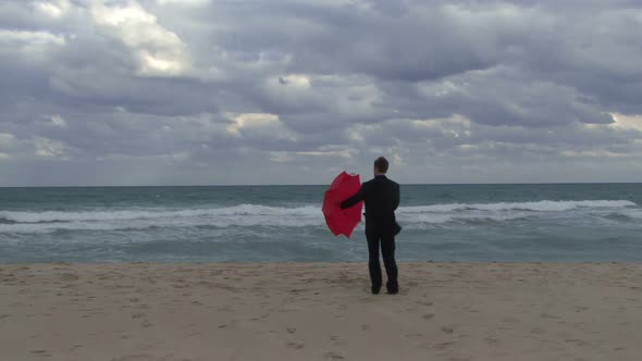 Male opening an umbrella on a beach alt