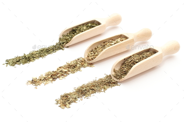Three spices - basil, oregano, dried parsley - on wooden spoons
