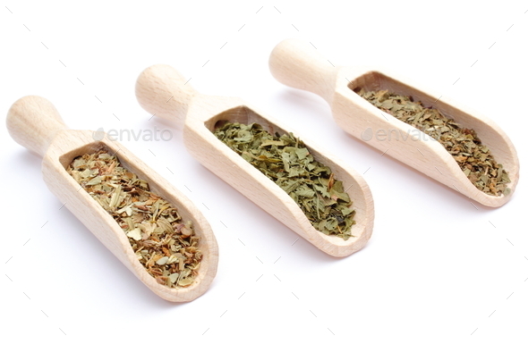 Three spices, basil, oregano, dried parsley on wooden spoons
