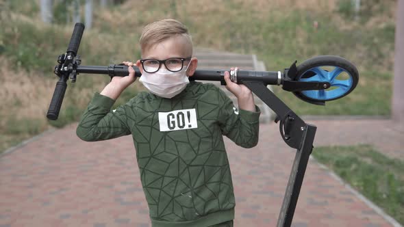 A boy carries a scooter over his head on the street during quarantine. alt
