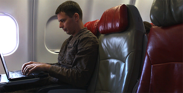 Man Working on Laptop on an Airplane and Going to 