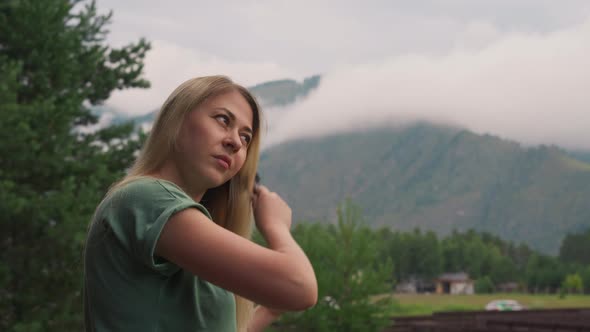 Attractive Woman Brushes Long Hair Against Misty Mountains alt