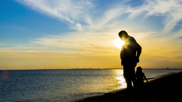 Silhouette Of Man With a Child On Sea Background
