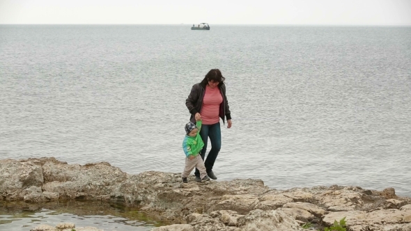 Mother And Baby Walking At The Seaside In Autumn