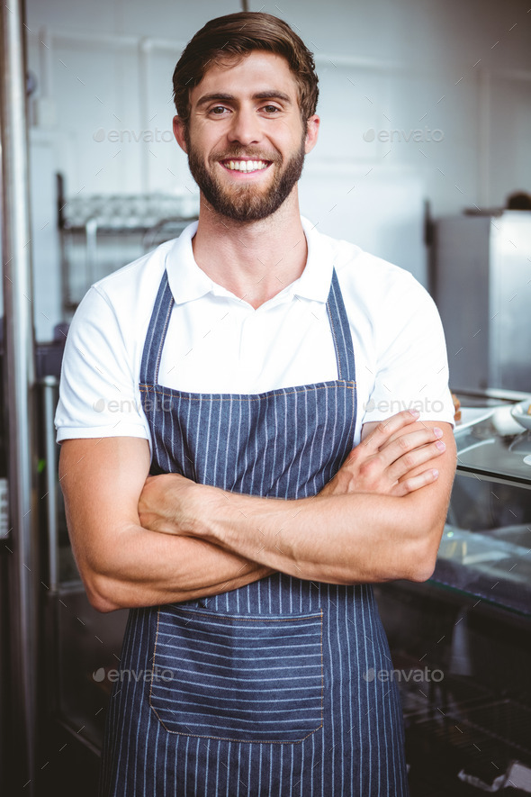 Smiling server in apron arm crossed at the bakery