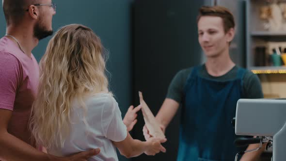 Back view of customers couple making order or buying coffee beans from barista in  stylish cafe. alt