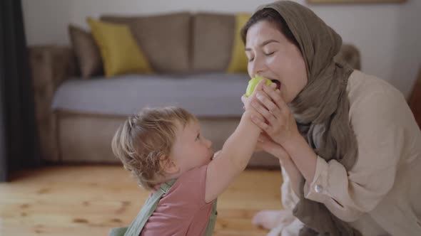 Little Boy Eating Green Apple Chewing and Sitting on Knees alt