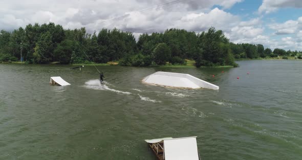 Wakeboarding in a Lake Near the Forest, Adult Man Surfs on the Water, Ride on a Wakeboarding Board alt