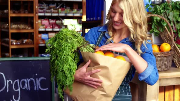 Portrait of smiling woman holding a grocery bag in organic section alt