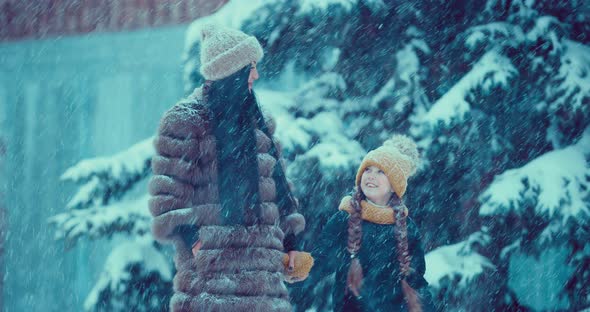 Happy Mom and Daughter Go to the Snowfall alt