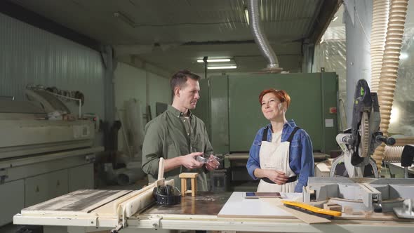 Man and Woman Joiners Using Digital Tablet While Working in Workshop