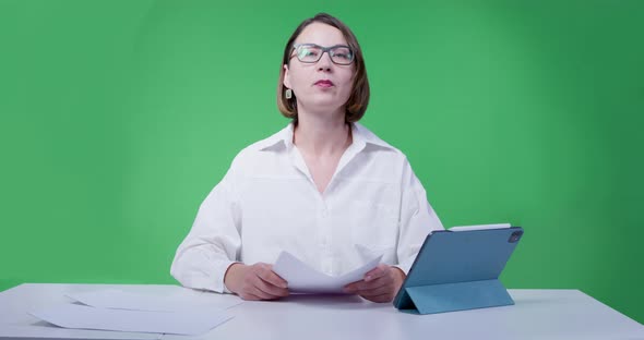 Young Woman in Glasses and White Shirt Leads a News Release on the TV Channel Green Chromakey on